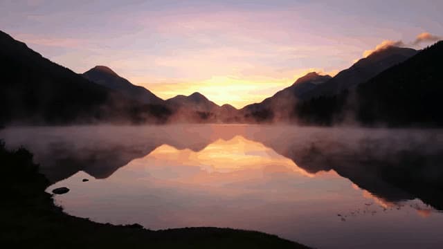 A serene sunrise over a misty mountain lake, the sky painted with hues of orange and pink, mist rising from the calm water as birds glide gracefully above.
